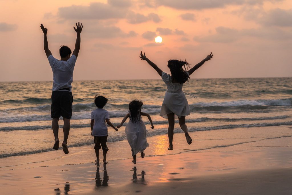 Famille en vacances profitant du coucher de soleil sur la plage pendant un séjour en camping à la Toussaint, moment de complicité et de détente en bord de mer.