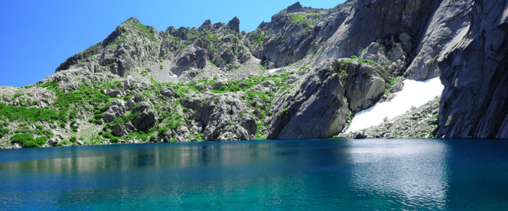 Lac de montagne aux eaux turquoise entouré de falaises rocheuses sur le GR 20 en Corse.