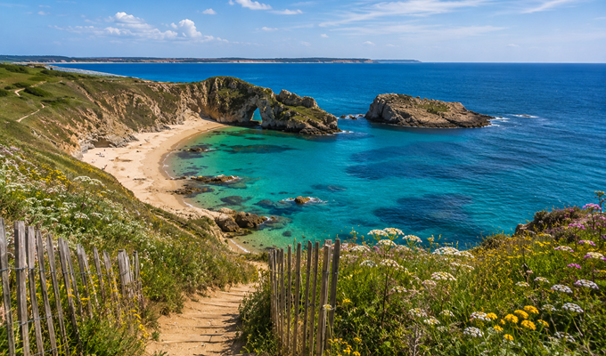Panorama du littoral français avec plage sauvage, falaises et eaux turquoise, idéal pour un séjour en camping proche de la nature.